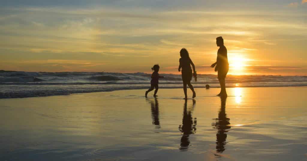 family playing on beach at dusk